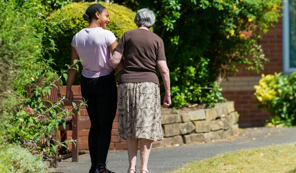 Resident And Staff Member Take A Walk In The Beautiful Sunny Garden