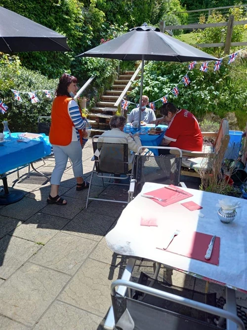 Residents outside sitting at garden furniture with a parassol up 