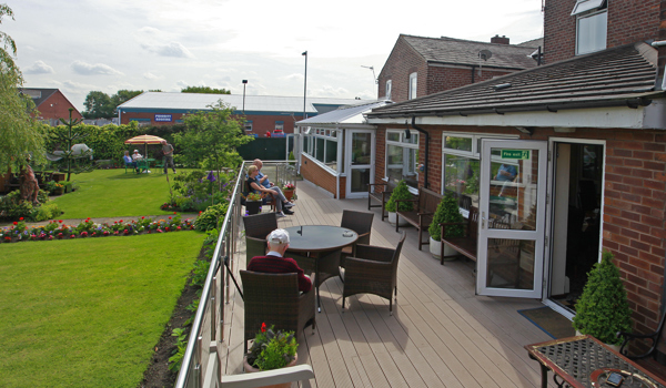 Residents are sat outside on the decked area in the sun