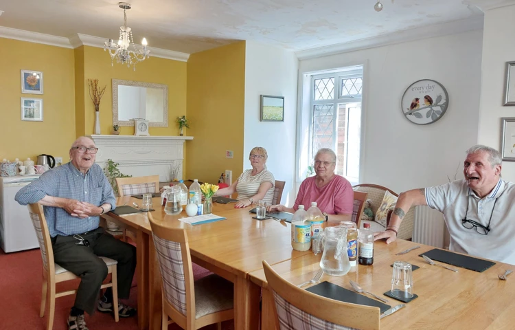 Happy Residents Sitting Round The Table Together