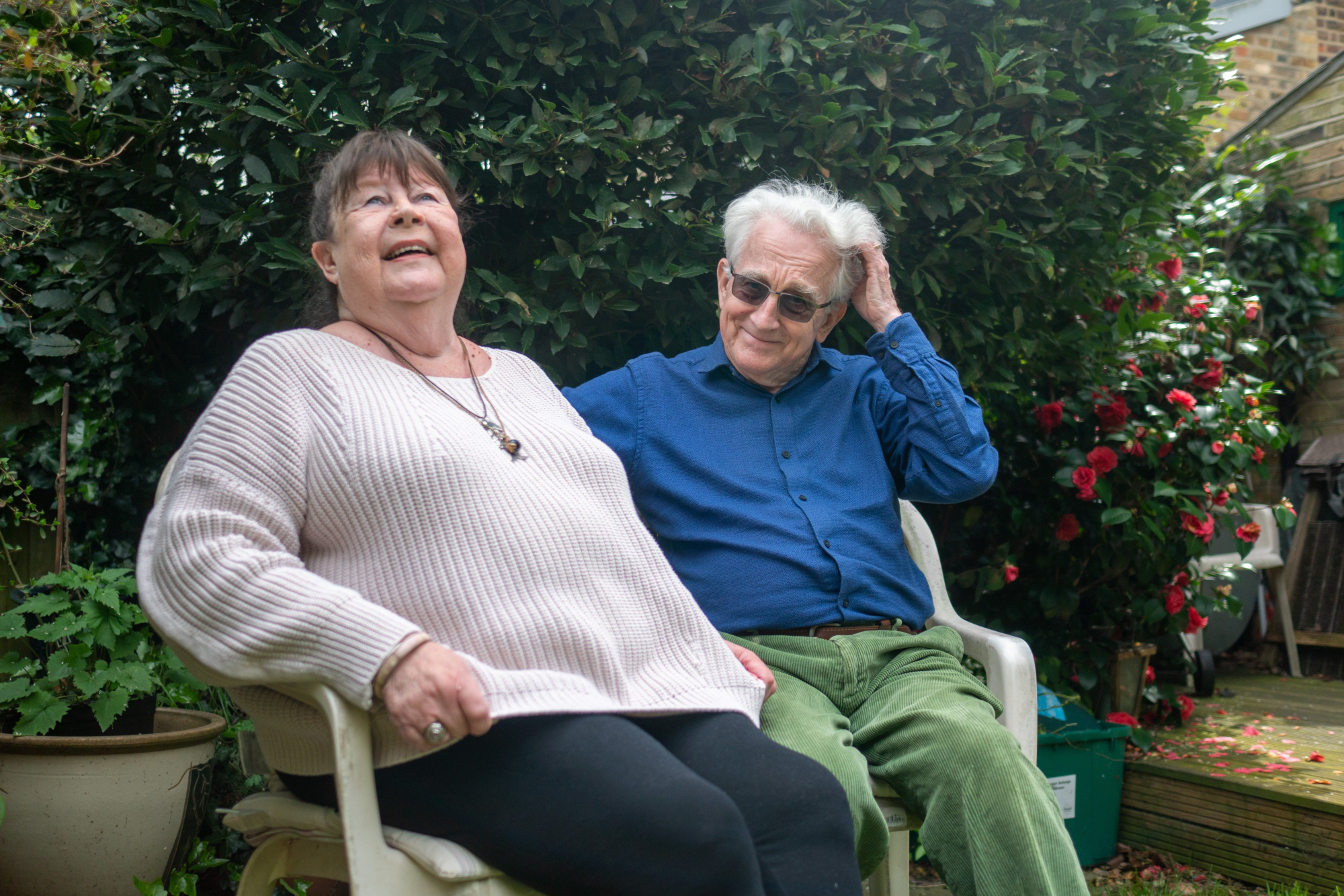 Older Woman And Man Sitting Together On A Bench In The Garden