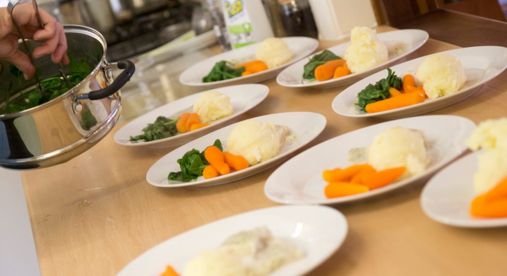 The house chef is plating up dinner for the residents