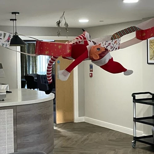 Elf on the shelf toy suspended from the ceiling