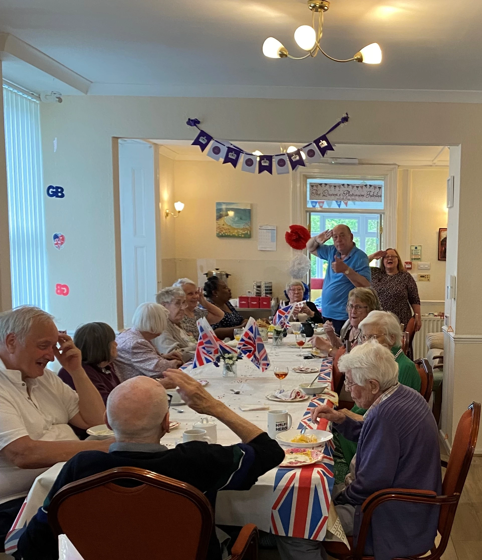 Residents at a long table celebrating the jubilee with one man saluting