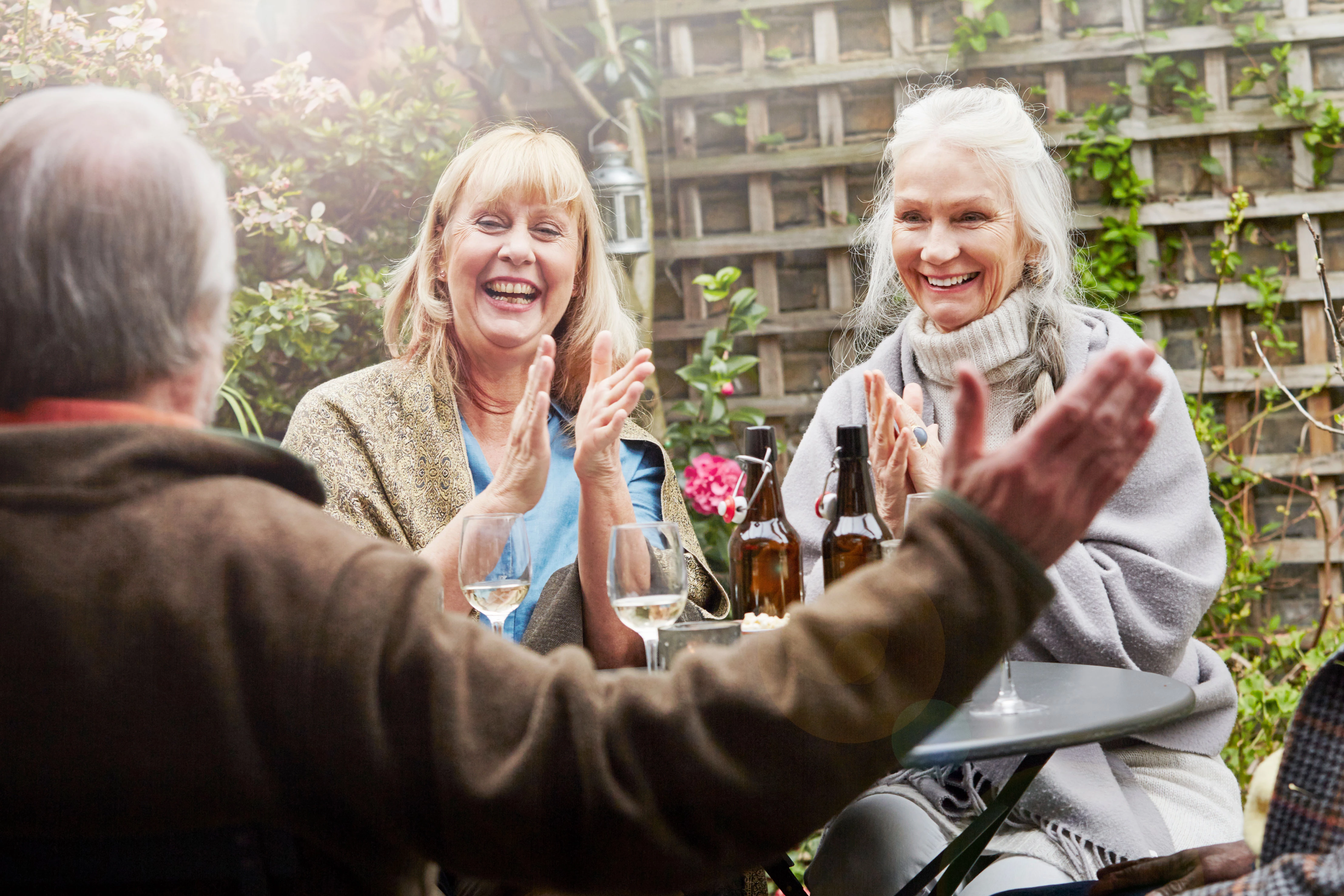 Happy Group Of People Sitting Around Having Drinks In The Garden