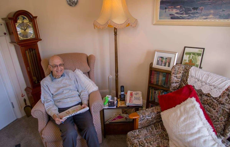 Smiling resident sitting in their room at Lade House