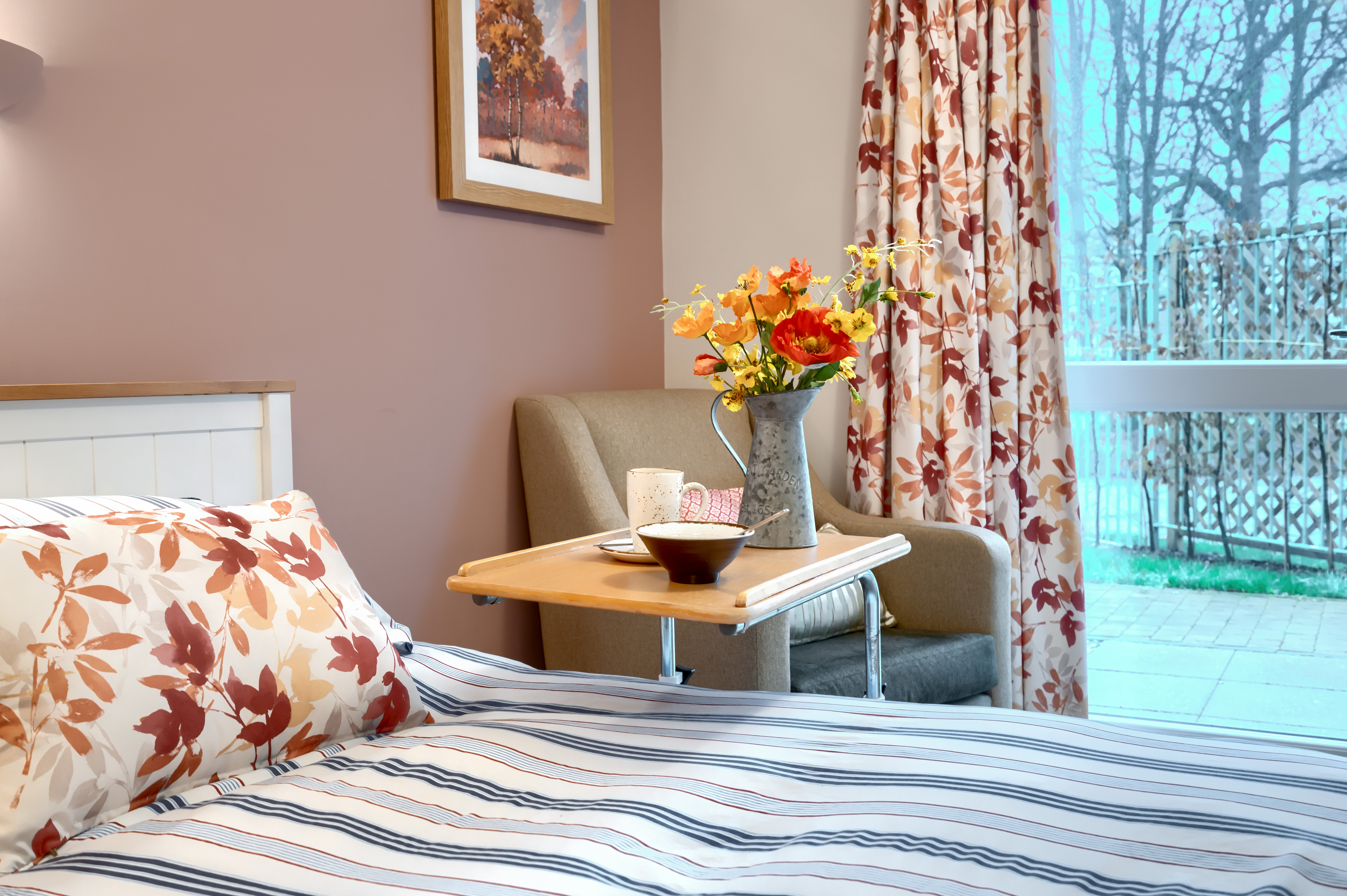 A beautifully decorated bedroom at Westall House with art, flowers and a garden view