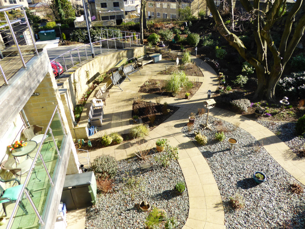 Outside view pebbled garden with shrubs and pots for residents of Ing Royde to enjoy