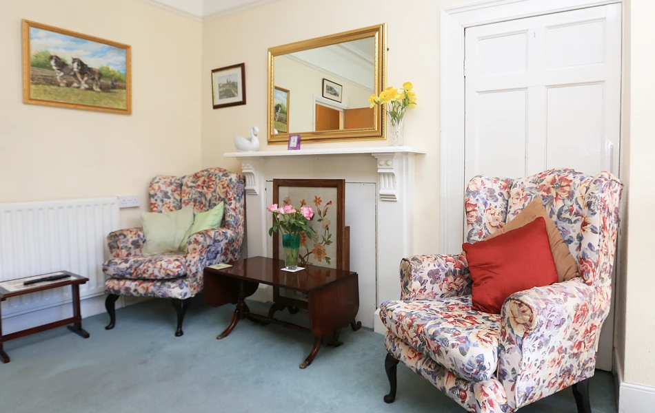 Chairs set to the side of a fireplace in the lounge