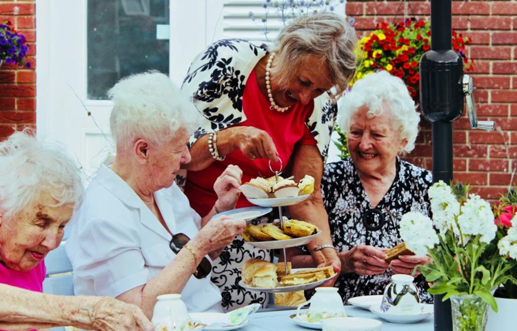 Residents are sat enjoying afternoon tea outside