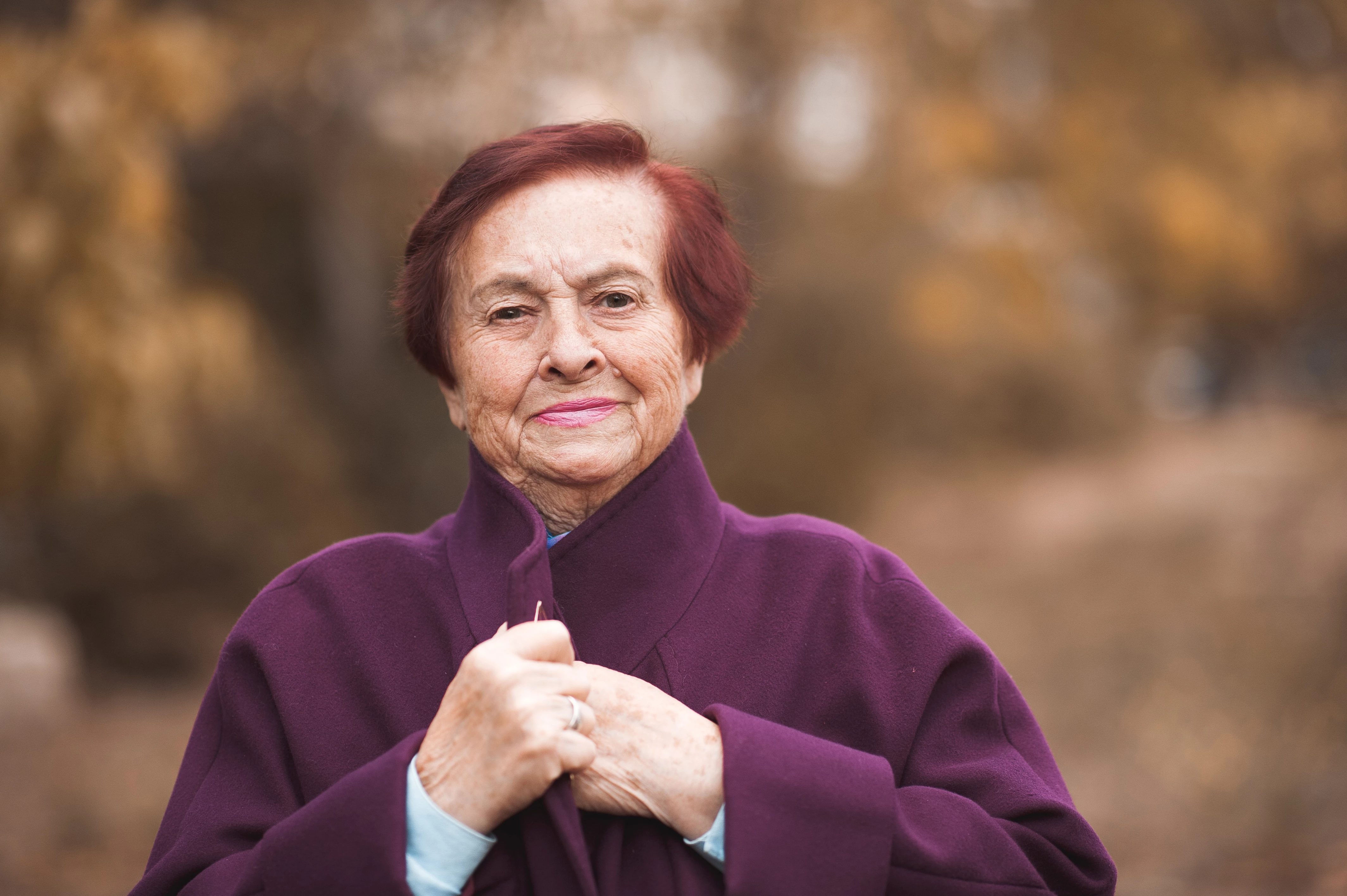 Smiling Older Woman Wrapped In Coat In Autumn