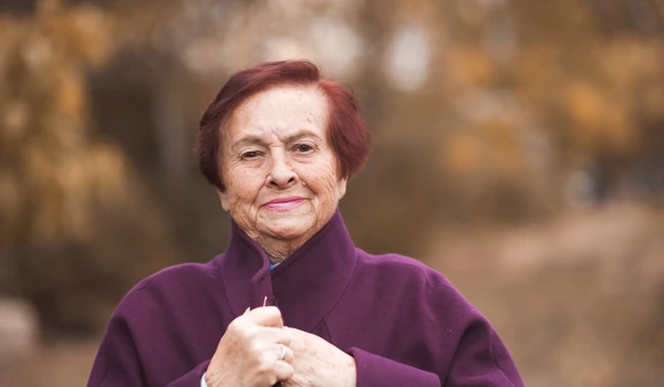 Smiling Older Woman Wrapped In Coat In Autumn