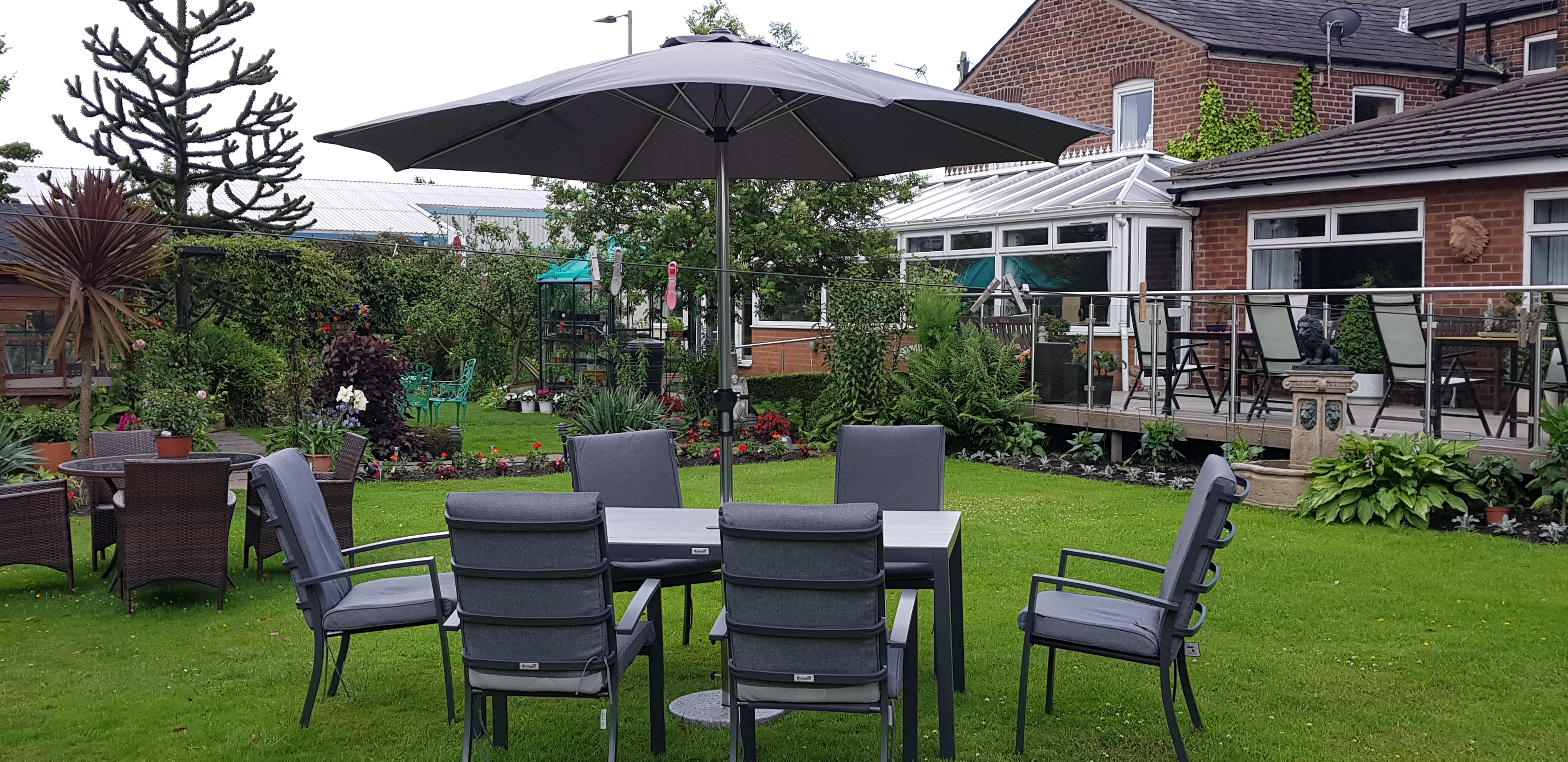 A garden table and chairs on the grass with a view of the balcony and decking