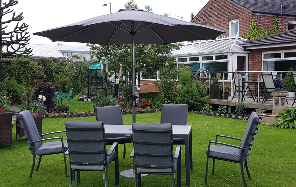 A garden table and chairs on the grass with a view of the balcony and decking