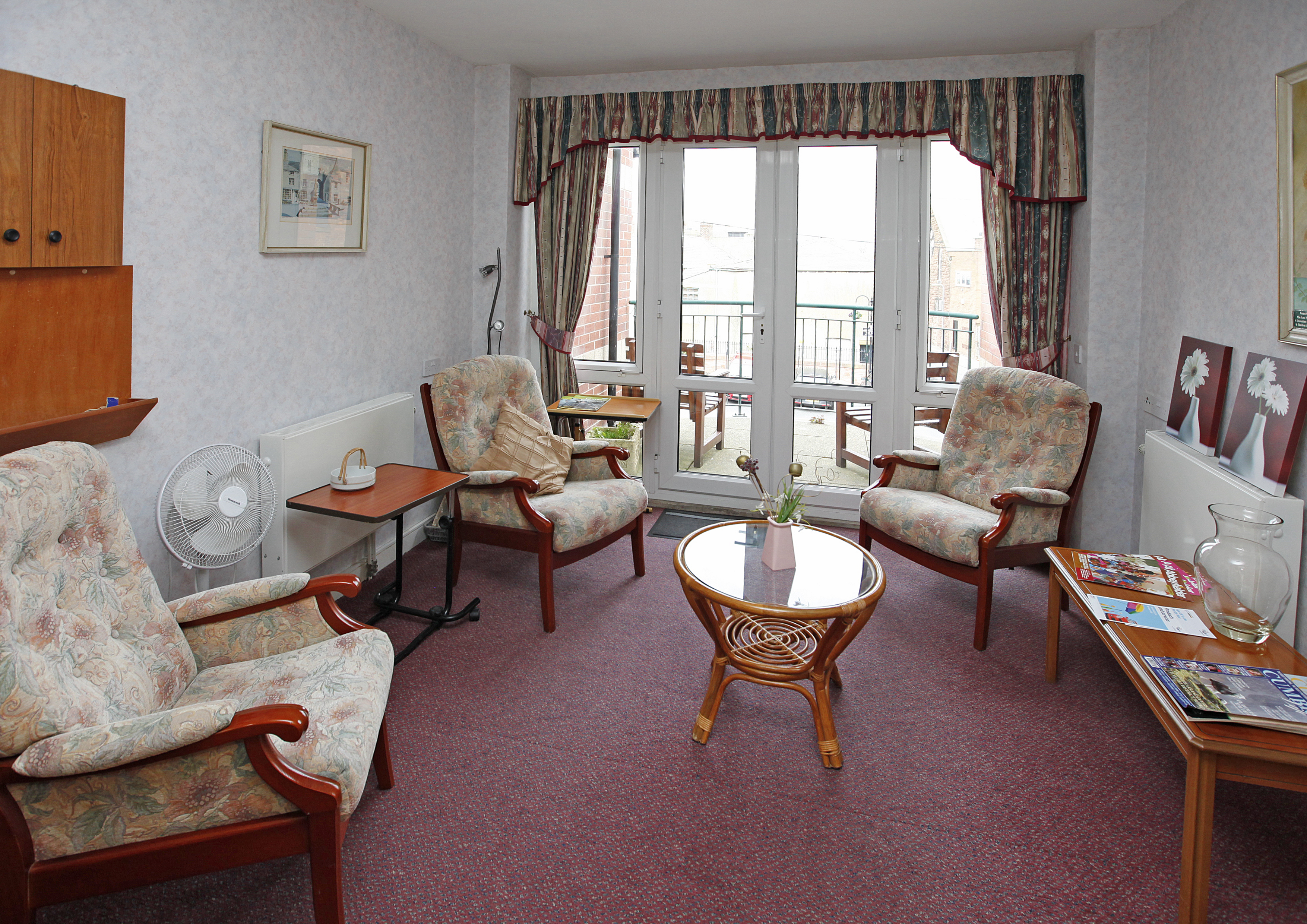 A large bright lounge with seating for residents at Millennium House, Barrow in Furness