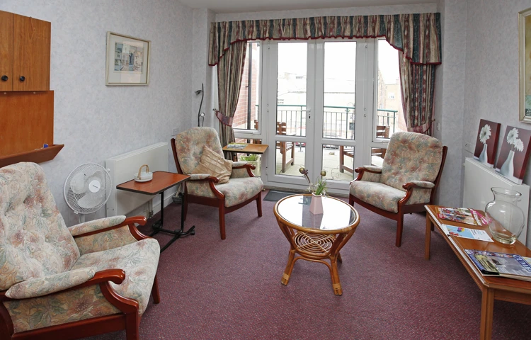 A large bright lounge with seating for residents at Millennium House, Barrow in Furness