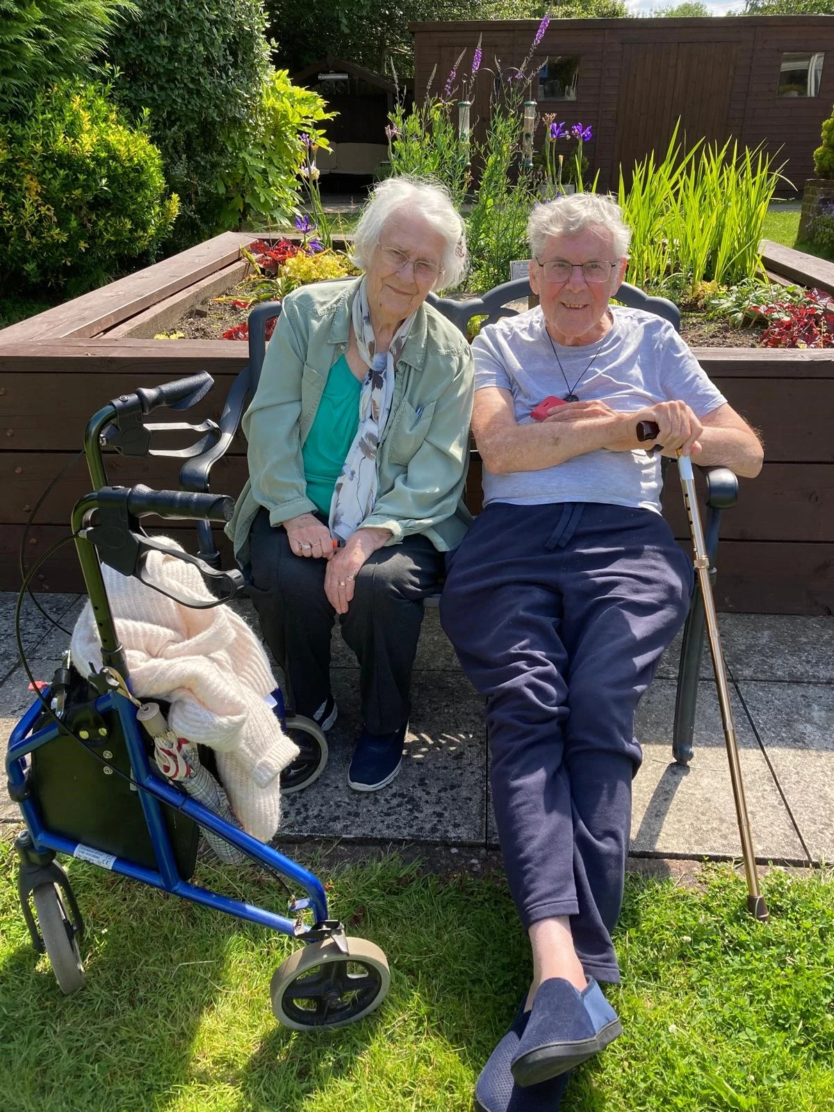 An older man and woman sitting on a bench smiling