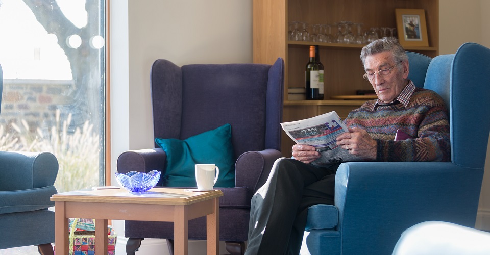 Resident sitting in armchair at Kift Lodge, Bristol BS15 3LQ