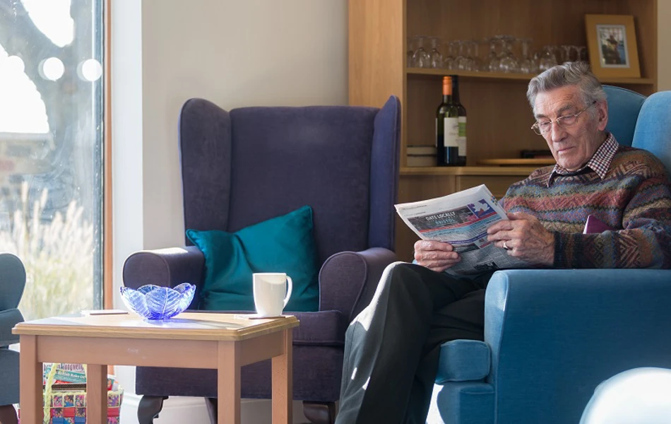 Resident sitting in armchair at Kift Lodge, Bristol BS15 3LQ