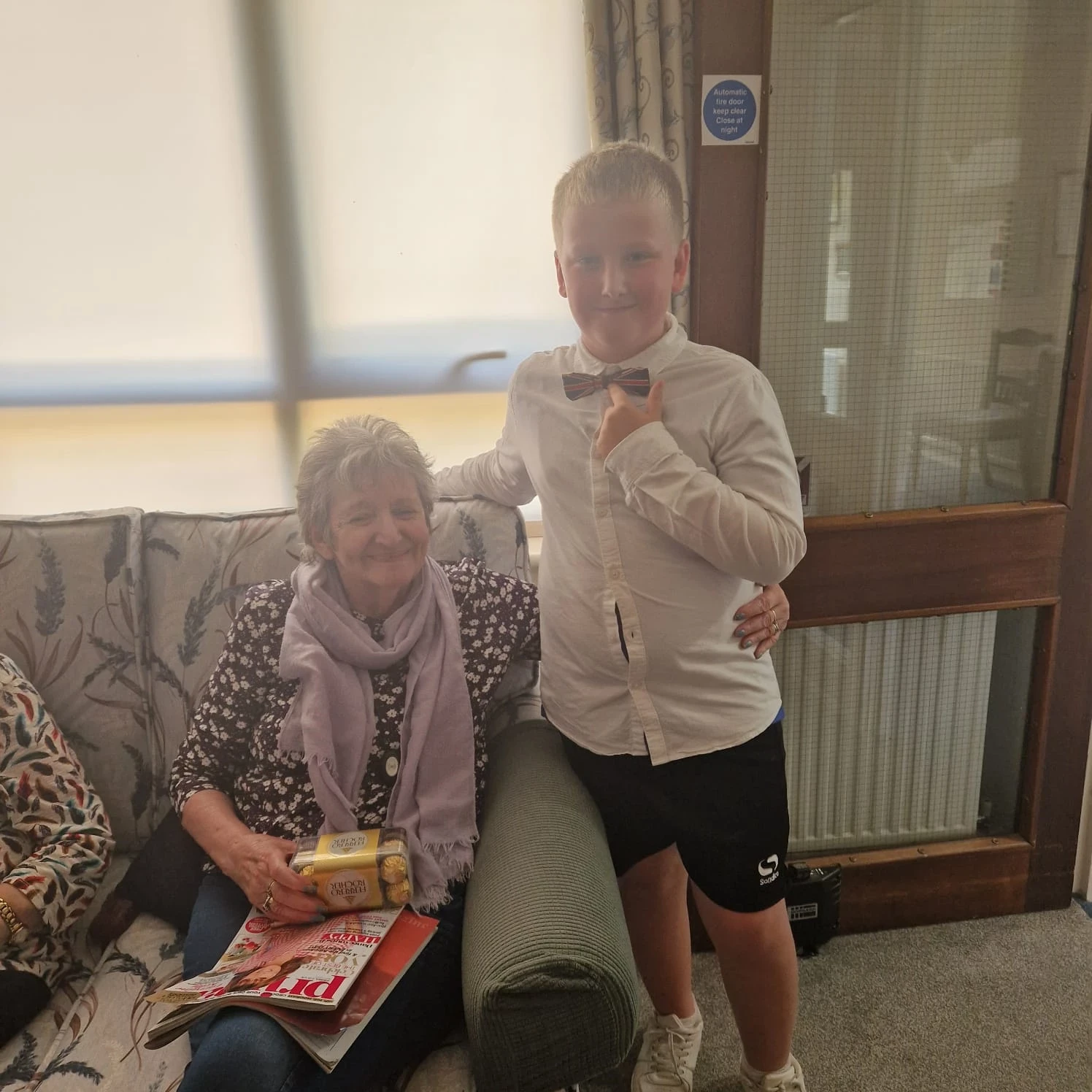 Child standing next to resident sitting down on a sofa with chocolates in their hand