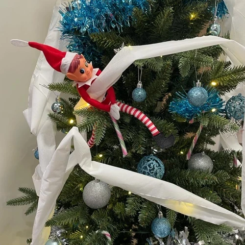 Elf on the shelf toy wrapped in toilet paper on a christmas tree