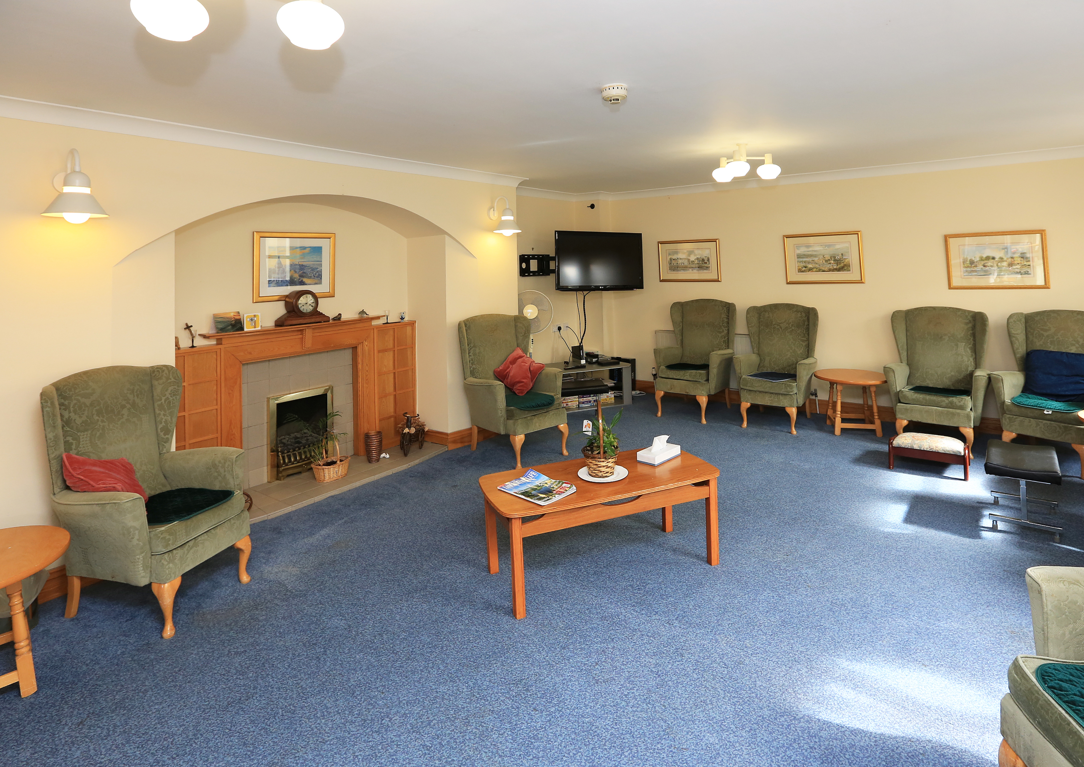 Large lounge area with blue carpet and green chairs at Chirnside House