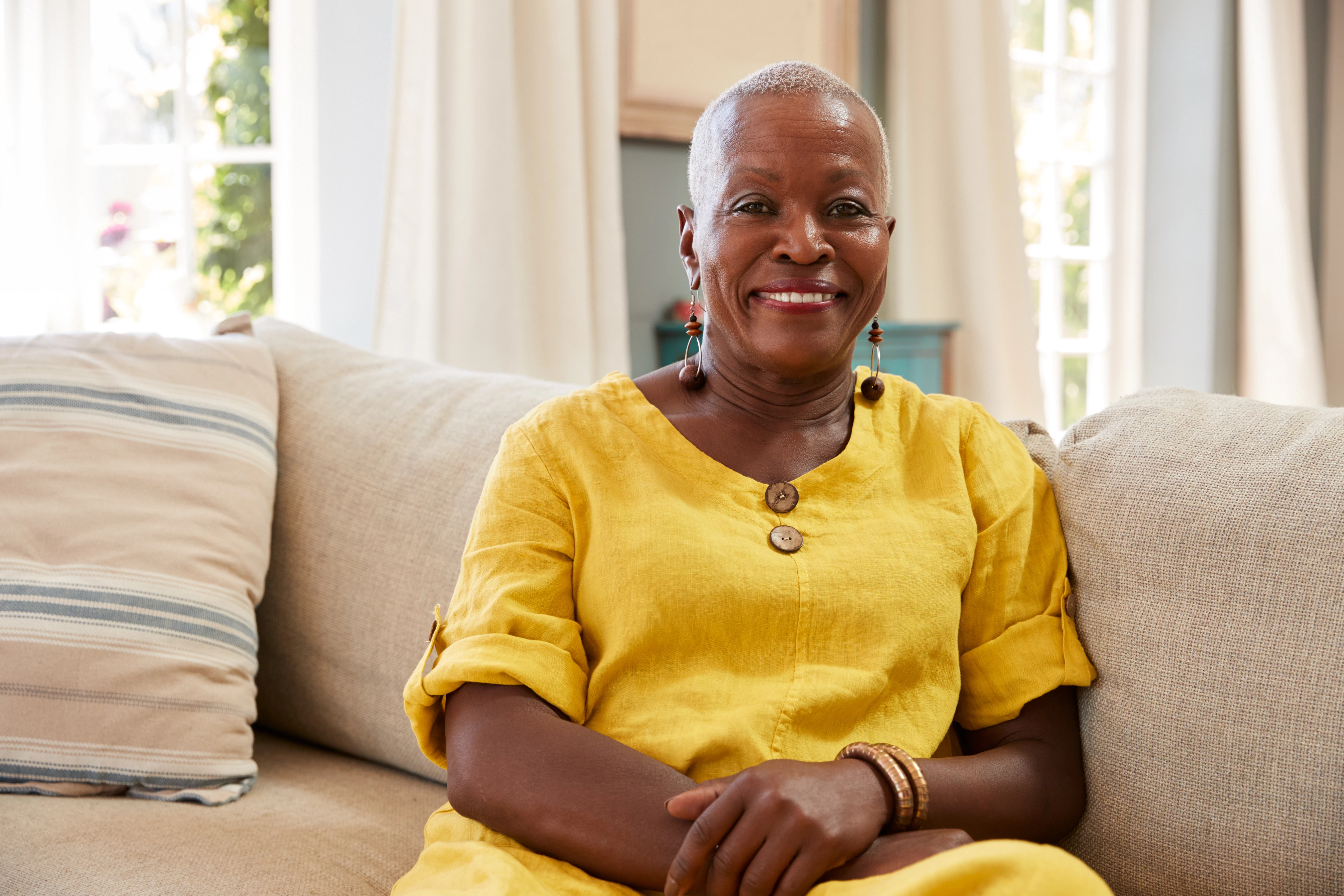 Smiling Older Woman Sitting On Sofa