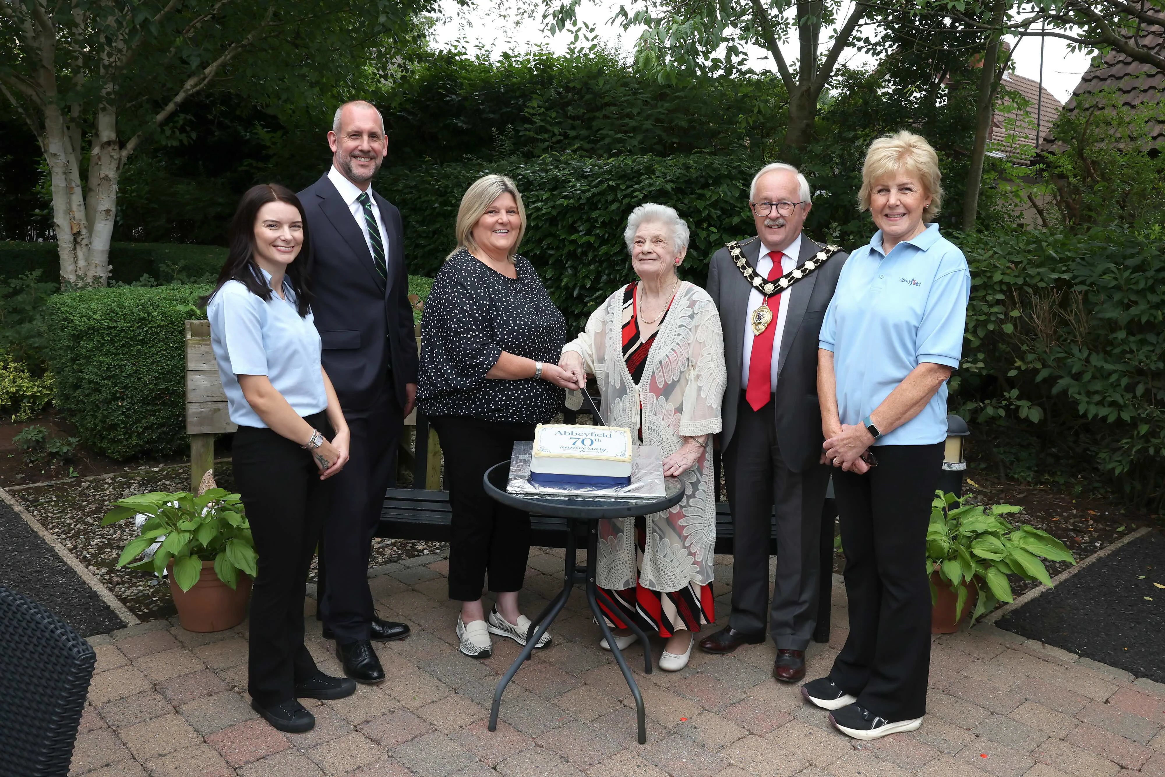 Members of the society stood with the mayor over a celebratory cake.