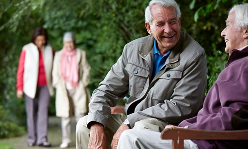 Happy Residents Sitting On Bench Outdoors