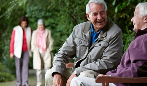 Happy Residents Sitting On Bench Outdoors