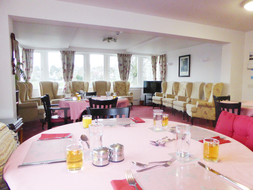 A table set for dinner with armchairs around the edge of the room