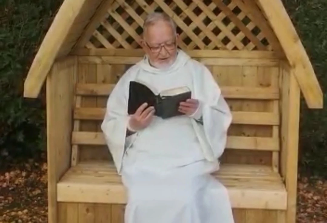 Canon Clyde relaxing in a garden chair reading the bible 