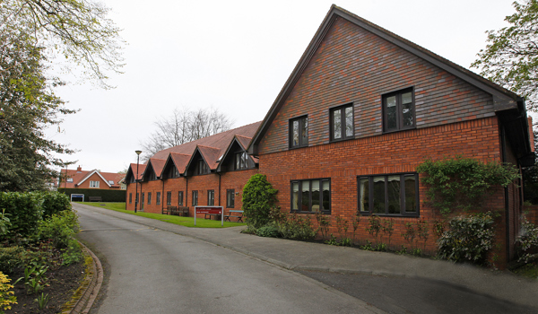 Large red brick house with trees and shrubs around it