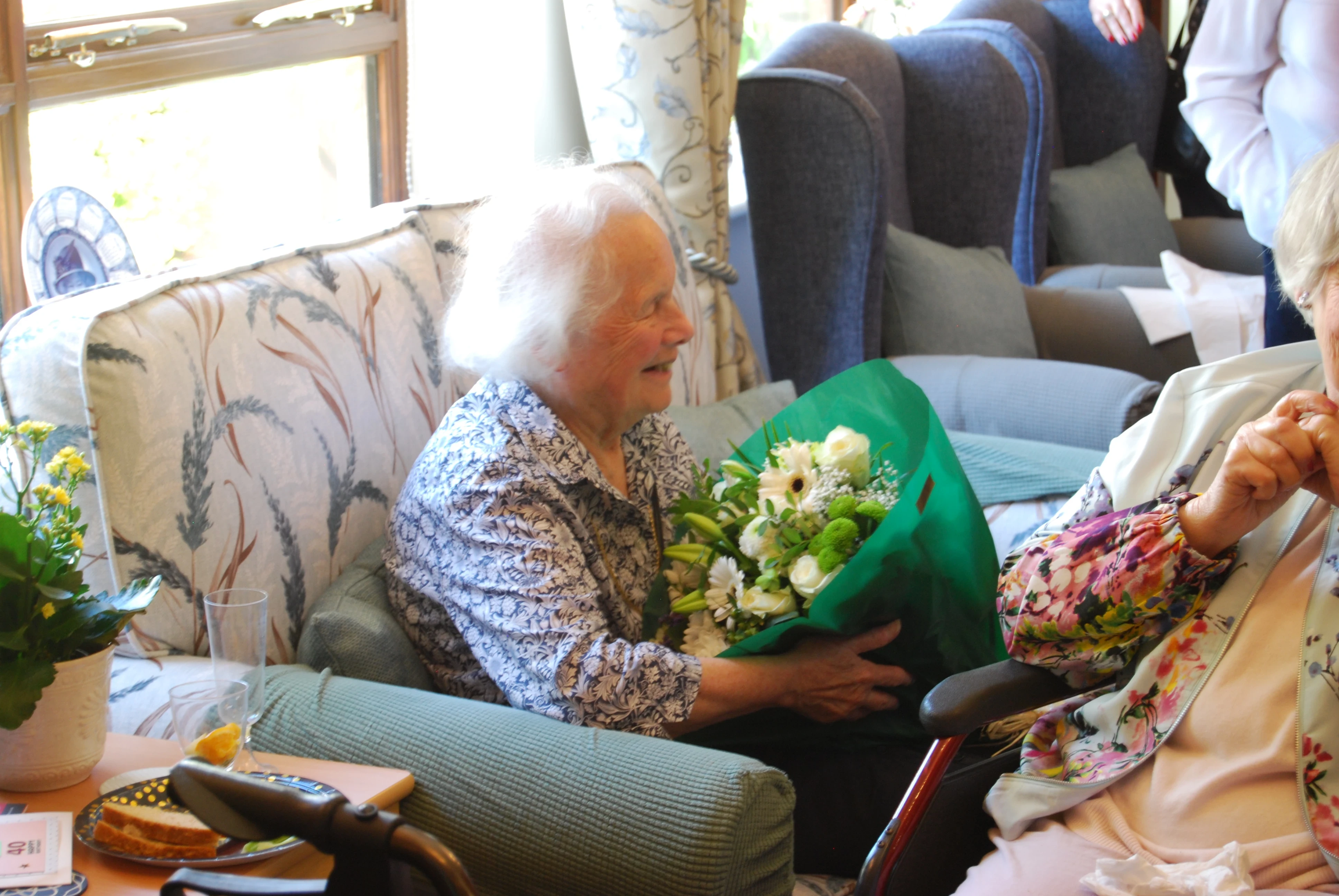 An older lady sitting down with a bunch of flowers