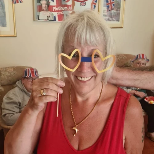 A woman posing with love heart glasses on a stick