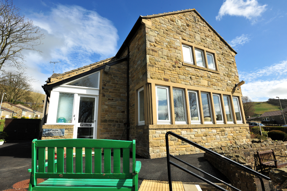 A green garden bench outside the front entrance of Abbeyfield House, Settle