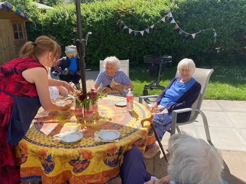 Serving residents on the patio with strawberry cakes and tea