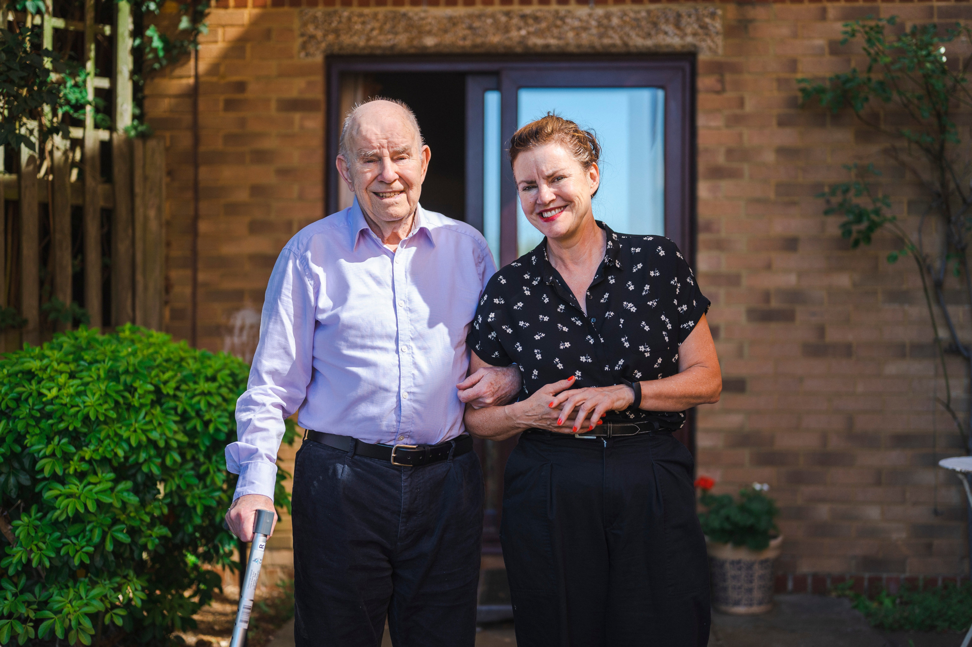 Older Man And Woman Arm In Arm Standing In The Garden