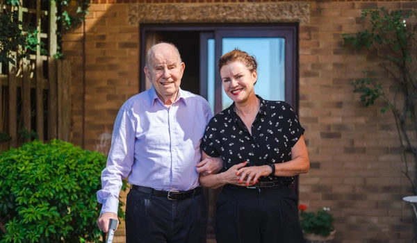 Older Man And Woman Arm In Arm Standing In The Garden