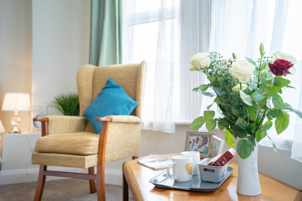 Bright resident room with arm arm chair and flowers