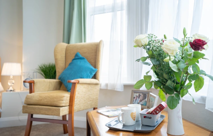 Bright resident room with arm arm chair and flowers