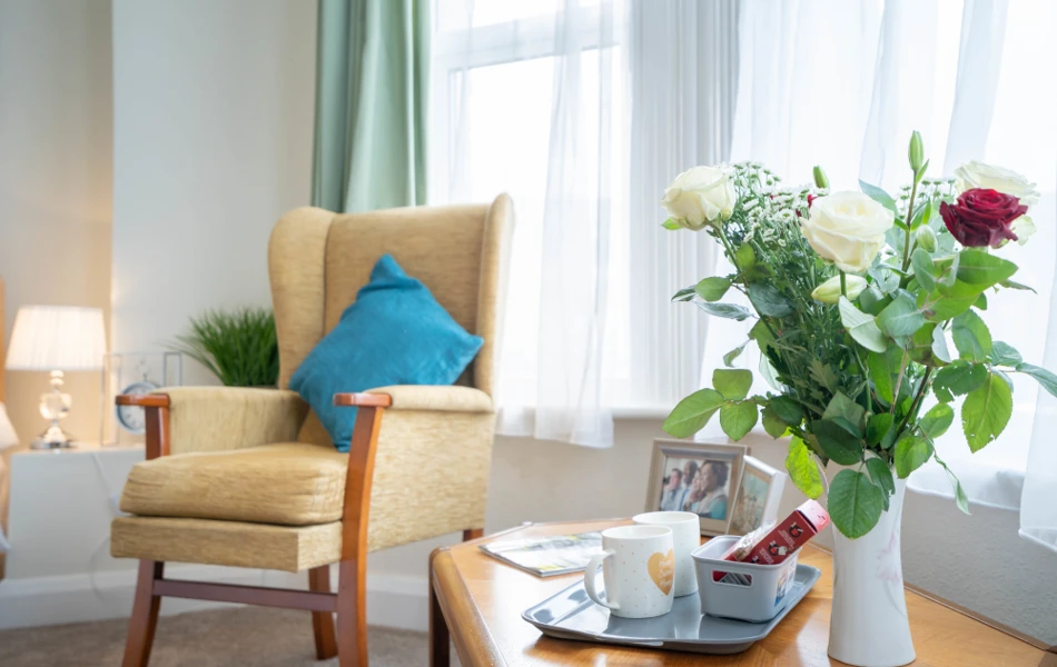 Bright resident room with arm arm chair and flowers