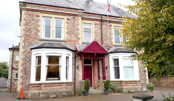 A large brick house with red porch and white bay windows