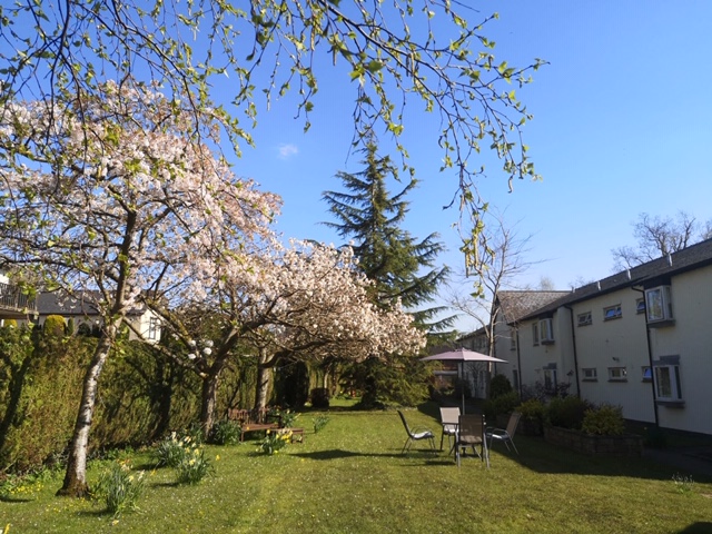 Sunny garden in bloom with table and chairs so residents can while away the hours in the sunshine