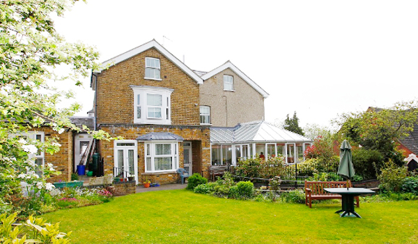 Beautiful sunny and large garden with seating and flowers in bloom at St Mary's House with rooms available to rent in Hemel Hempstead