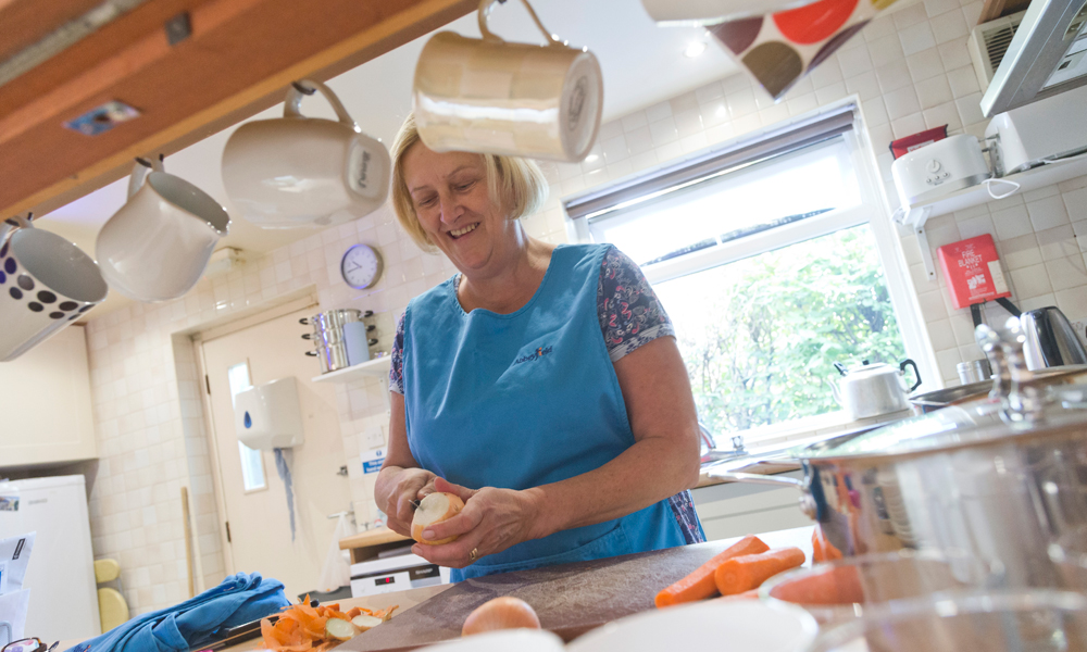A member of staff in the kitchen peeling vegetables for dinner