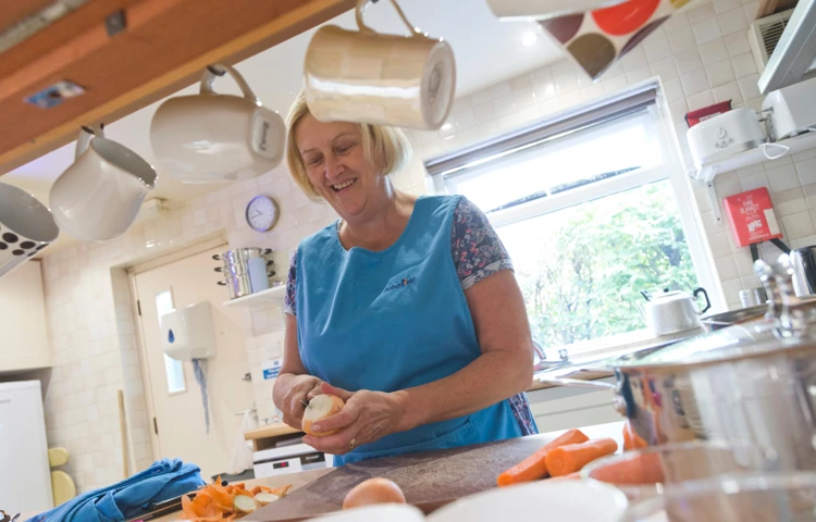 A member of staff in the kitchen peeling vegetables for dinner