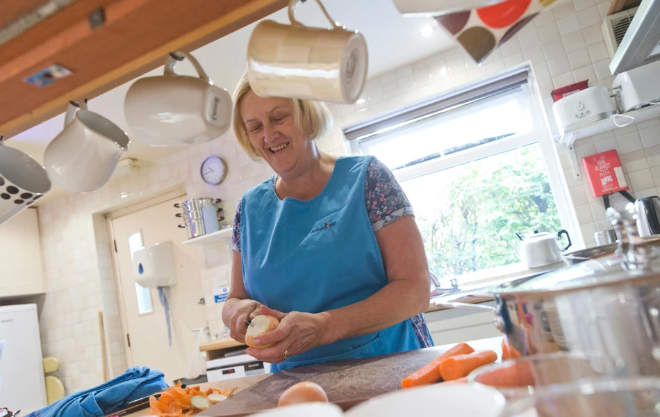 A member of staff in the kitchen peeling vegetables for dinner