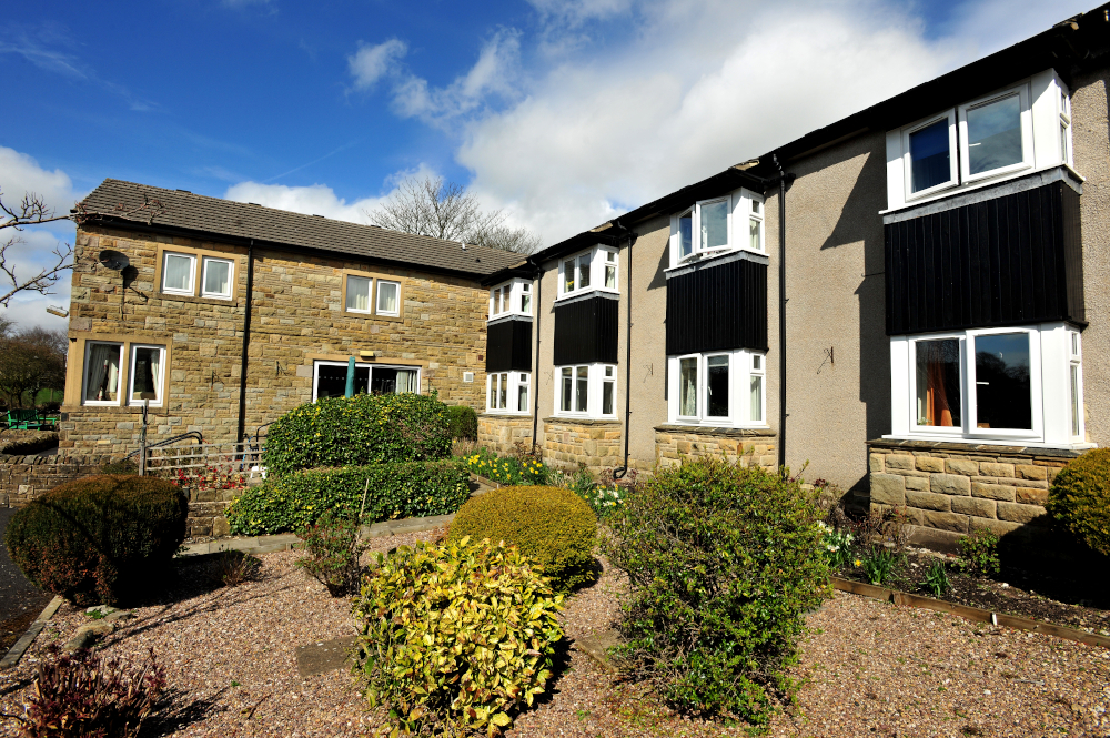 Garden area with shrubs under the house windows outside Abbeyfield House, Settle