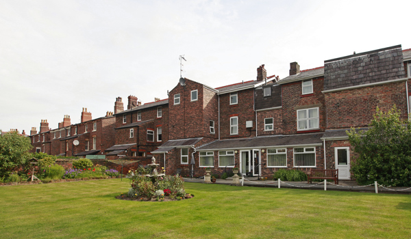 Large red brick house with garden and bird bath